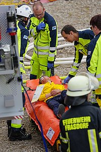 Person auf einer Trage liegend während der Behandlung durch med. Fachpersonal