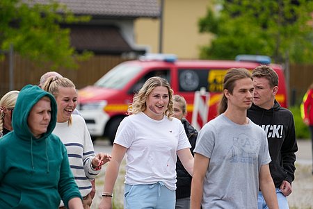 Personengruppe mit einer Person im Mittelpunkt, die eine dargestellte Verletzung im Gesicht hat