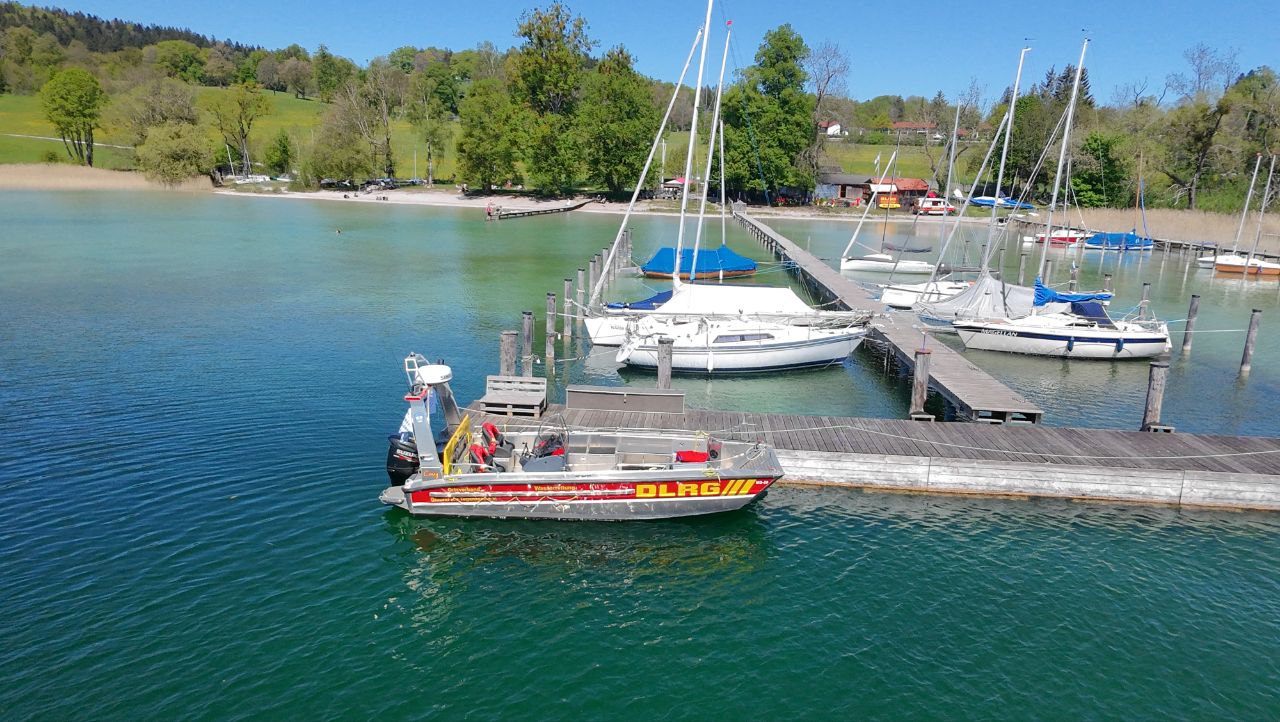 auf dem Bild ist das Motorrettungsboot „Conny“ mit dem Funkrufnamen „PELIKAN Gmund 99/1“ am Steg an der Station bei sonnigem Wetter zu sehen
